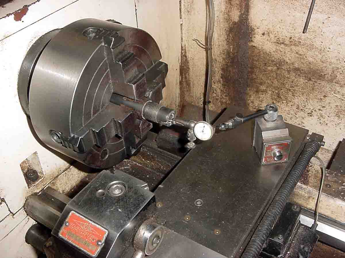 A dial indicator is used to center the barrel in the four-jaw chuck.